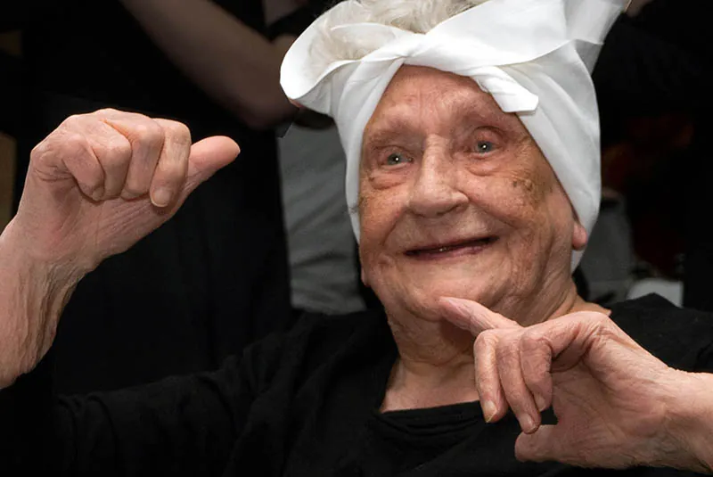 Oudere dame in klederdracht lacht in de camera